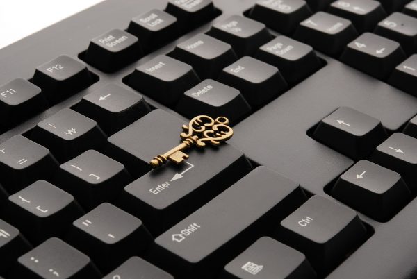Image of a computer keyboard with a gold key lying on top.