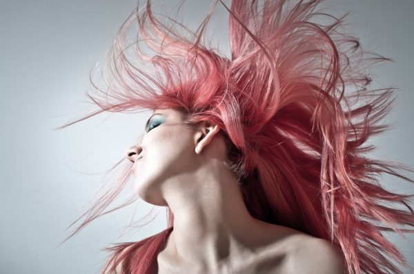 Girl with pink hair flipping her hair. 